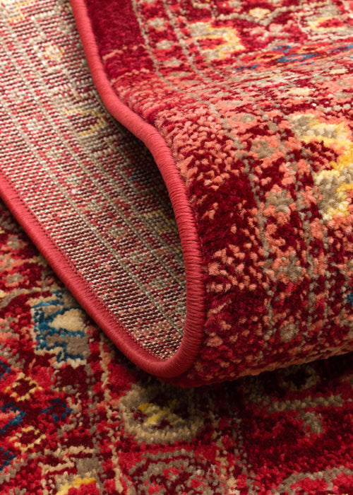 Load image 1 in gallery view. Red traditional rug with a distressed floral medallion pattern and blue and gold accents, shown folded to reveal backing.