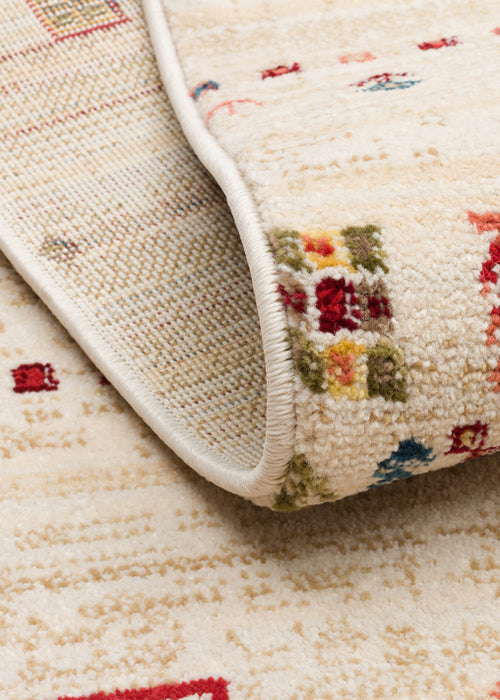 Load image 1 in gallery view. Cream rug with a folded corner revealing a multi-colored geometric pattern of red, blue, and green squares.