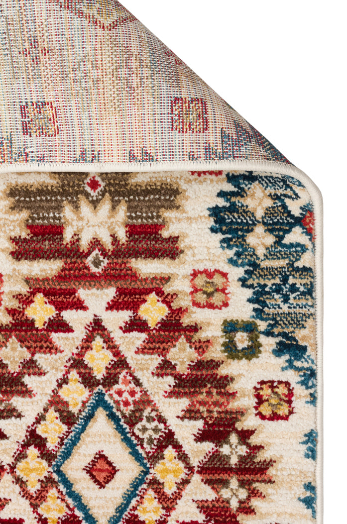 Cream-colored rug with a multi-colored geometric tribal pattern in red, blue, and yellow, shown with a folded corner.
