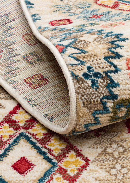Load image 1 in gallery view. Folded corner of a cream rug featuring a multi-colored geometric pattern in red, blue, and yellow on a white background.
