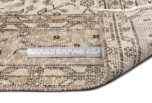 Bild 1 in Galerieansicht laden. A metal ruler sits on the Coaluon - Vintage Floral Rug (5'8 x 9'1), its corner lifted to display the flatwoven construction, thickness, and texture; the ruler shows both inch and centimeter measurements.