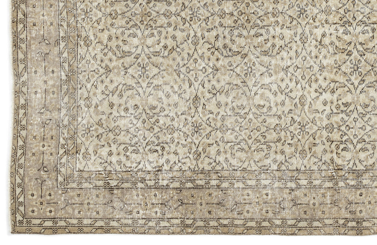 A close-up of the Coaluon - Vintage Floral Rug (5'8 x 9'1) shows beige and taupe tones with an intricate floral and geometric pattern, a detailed border, and a soft, worn texture that reflects its Anatolian heritage.