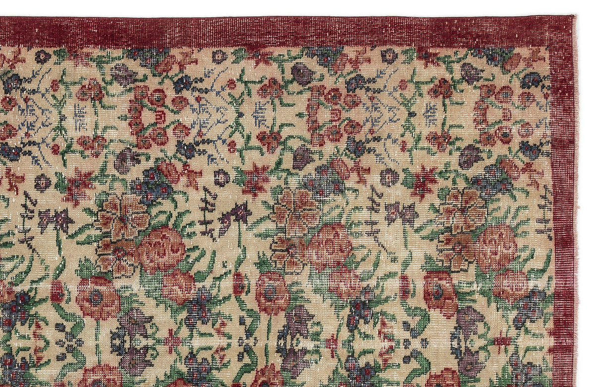 Beige rug with a distressed floral pattern in red, green, and blue, featuring a solid dark red border.