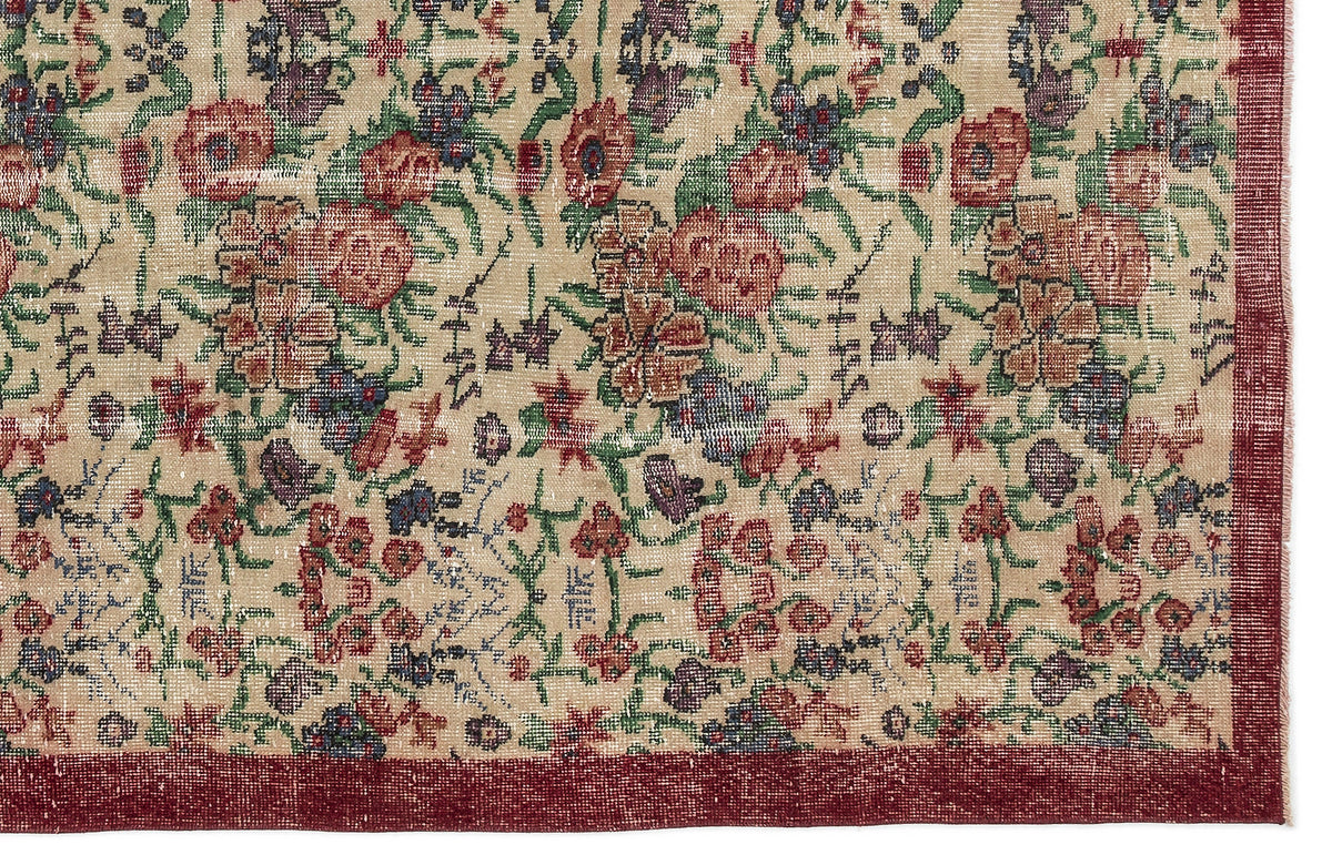 Beige rug with a distressed floral pattern in red, green, and purple, featuring a solid dark red border.