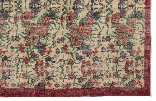Load image 1 in gallery view. Beige rug with a distressed floral pattern in red, green, and purple, featuring a solid dark red border.