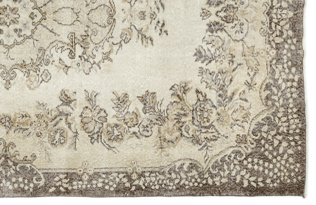 Cream and brown rug with a distressed floral medallion pattern and a detailed border.