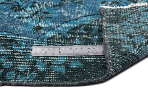 Load image 1 in gallery view. Teal and black distressed floral rug with a folded corner and a metal ruler for scale on a white background.