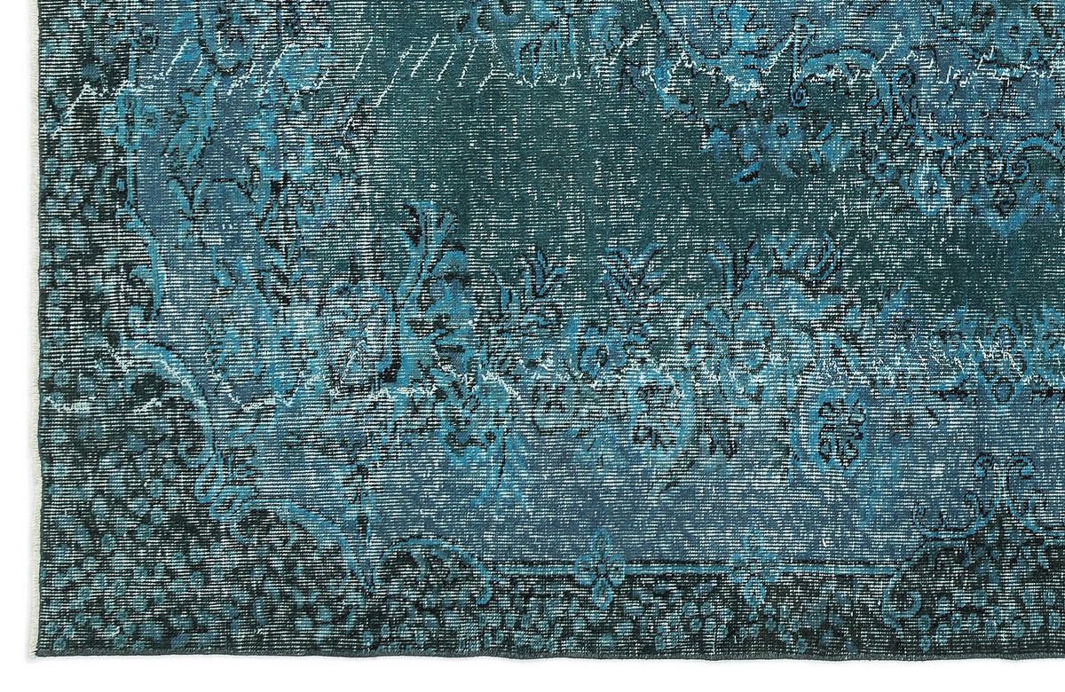 Teal and black distressed rug with a traditional floral medallion pattern and fringed edge.