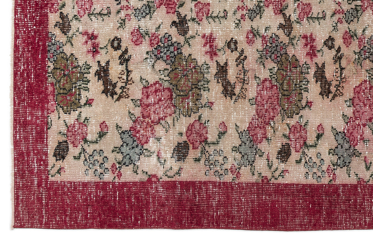 Distressed beige rug with a red floral pattern and a solid red border.