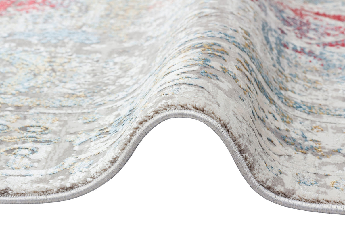 Distressed beige rug with a faded floral medallion pattern in red, blue, and yellow, shown folded on a white background.