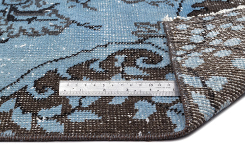 Load image 1 in gallery view. Blue and dark brown distressed floral rug with a folded corner and a metal ruler for scale on a white background.