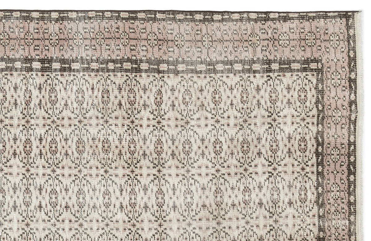 Dusty pink and charcoal grey rug with a traditional repeating medallion pattern and a decorative border.