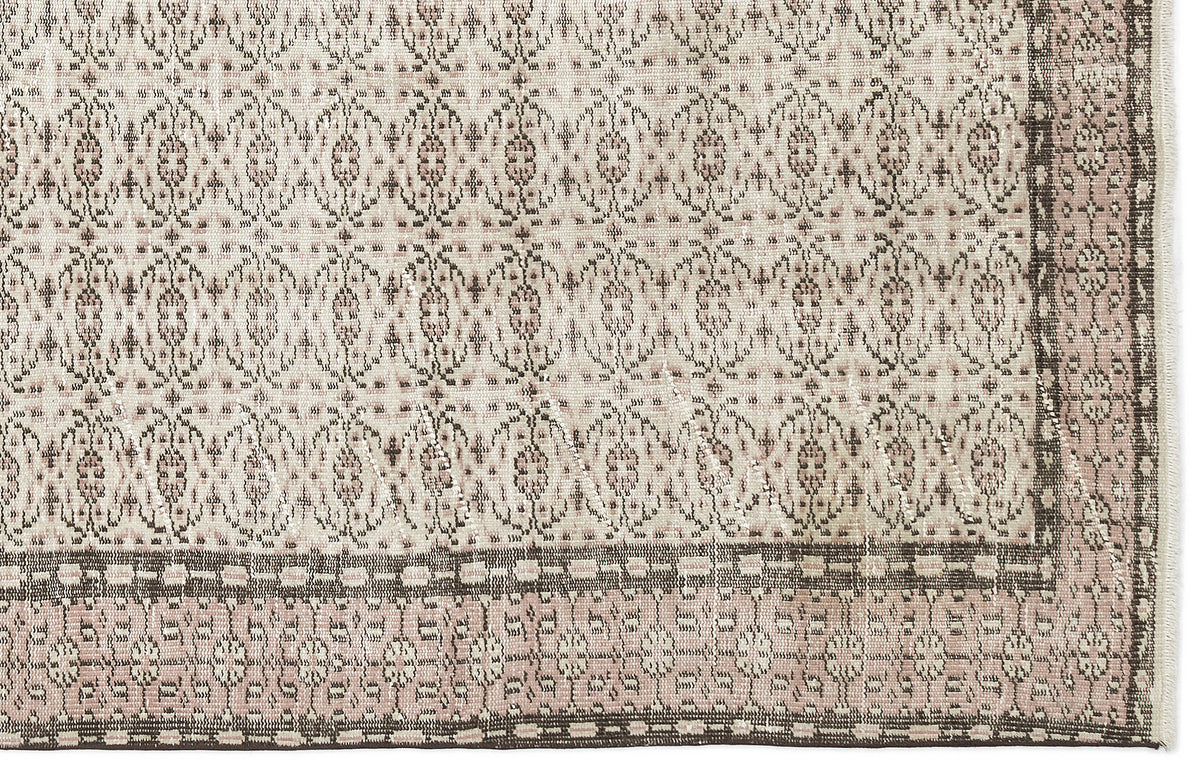 Beige and dusty rose rug with a repeating geometric medallion pattern and a dark brown border.