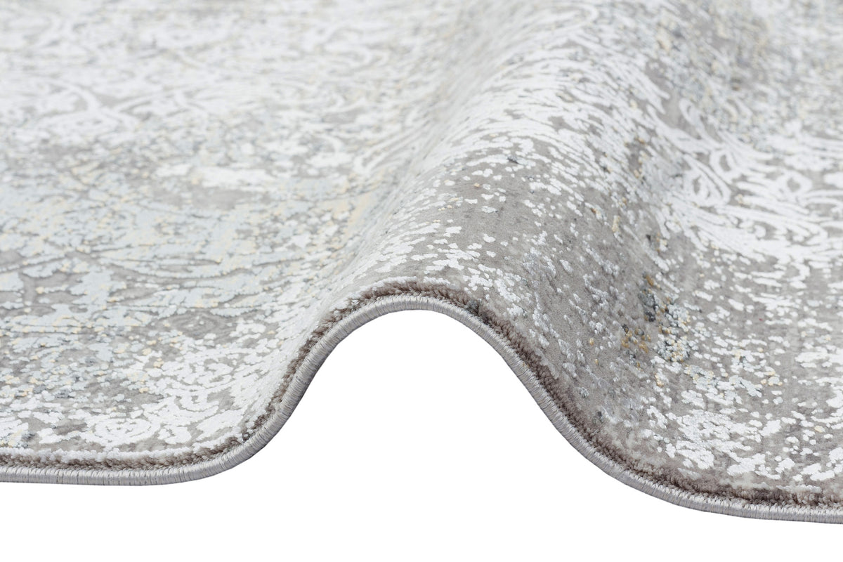 Grey and white rug with a distressed traditional medallion pattern and a serged edge, shown folded on a white background.