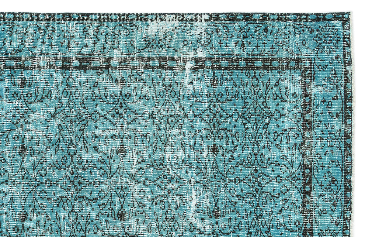 Turquoise and black distressed rug with a traditional ornate floral medallion pattern and a geometric border.