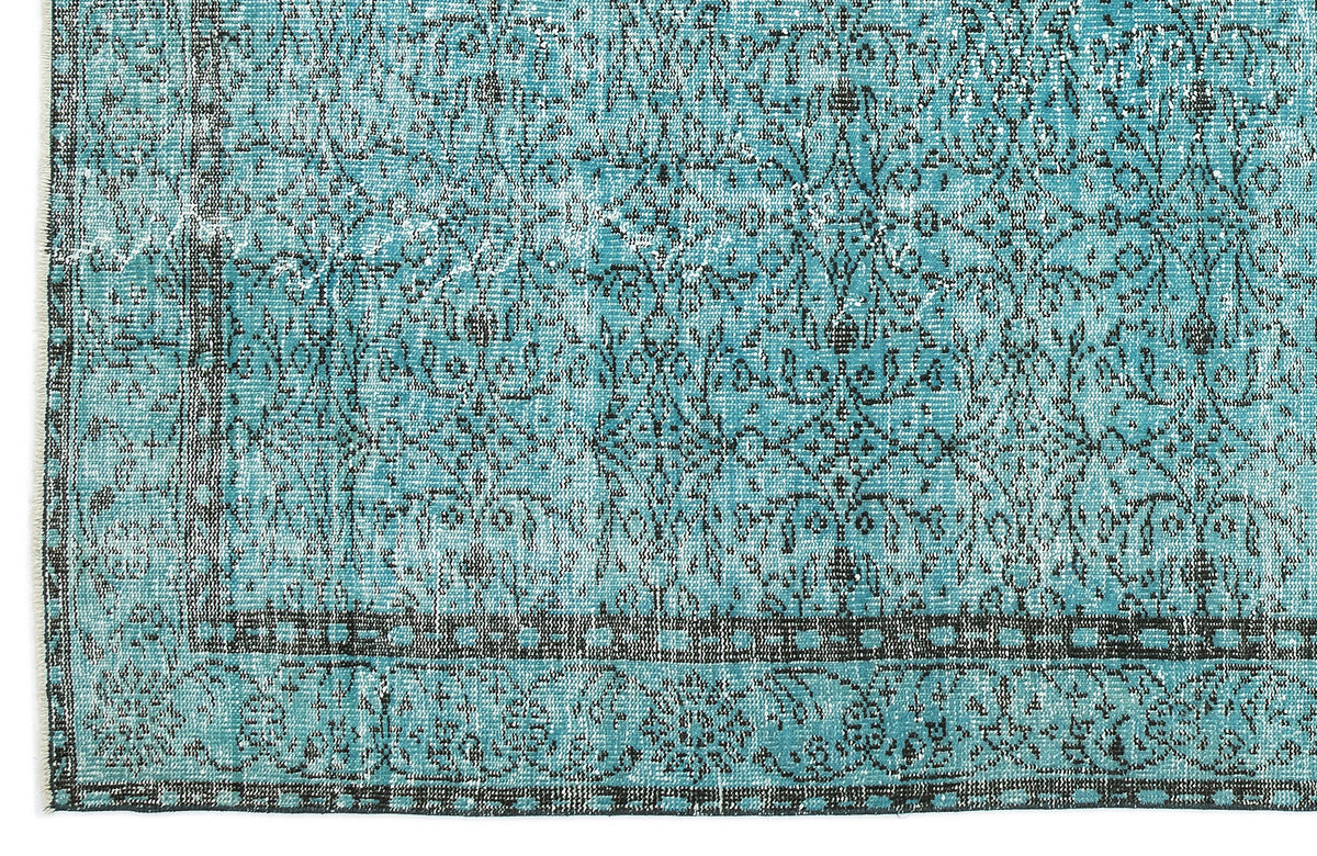 Turquoise and black distressed rug with a traditional floral medallion pattern and a geometric border.