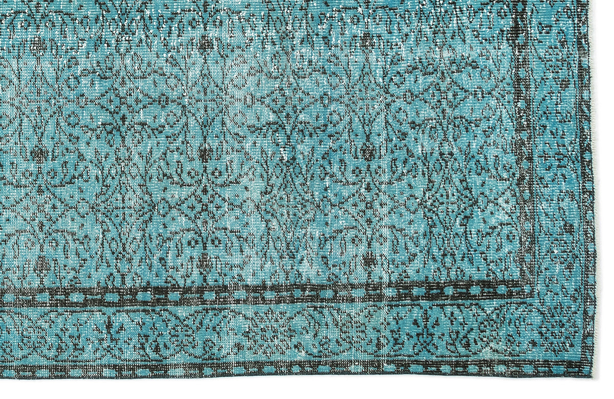 Turquoise and black distressed rug with a traditional floral medallion pattern and a geometric border.
