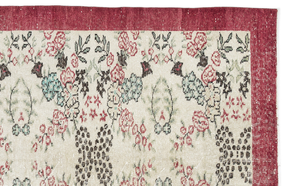 Cream rug with a red border and a distressed floral pattern in shades of red, green, and dark brown.