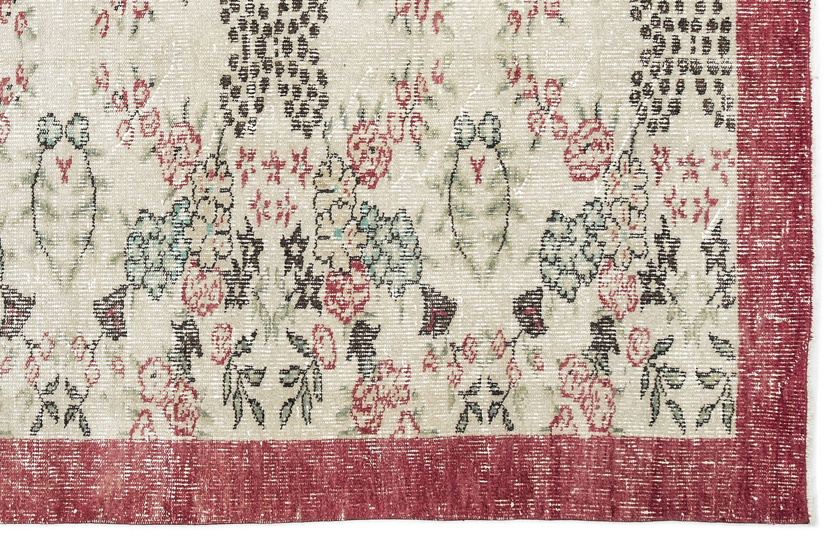 Distressed cream rug with a floral pattern in red, green, and black, featuring a wide red border.