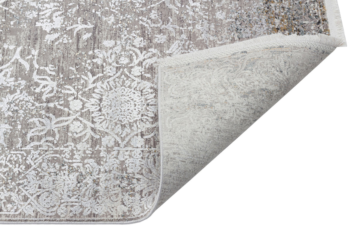 Grey and white distressed floral medallion rug with a folded corner showing the underside, isolated on white.
