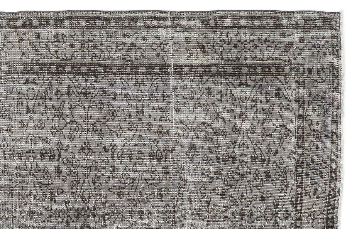 Grey and charcoal distressed rug with a traditional floral vine pattern and a geometric border.