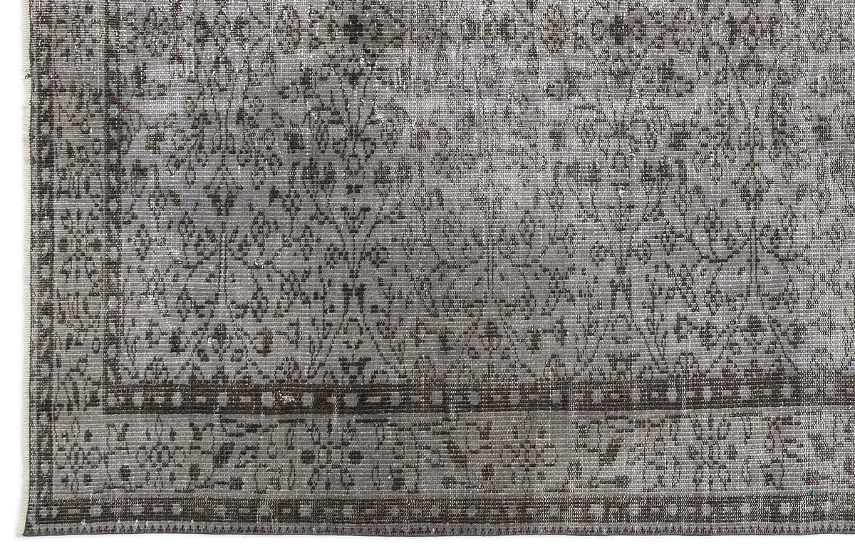 Grey and charcoal distressed rug with a traditional floral medallion pattern and a geometric border.