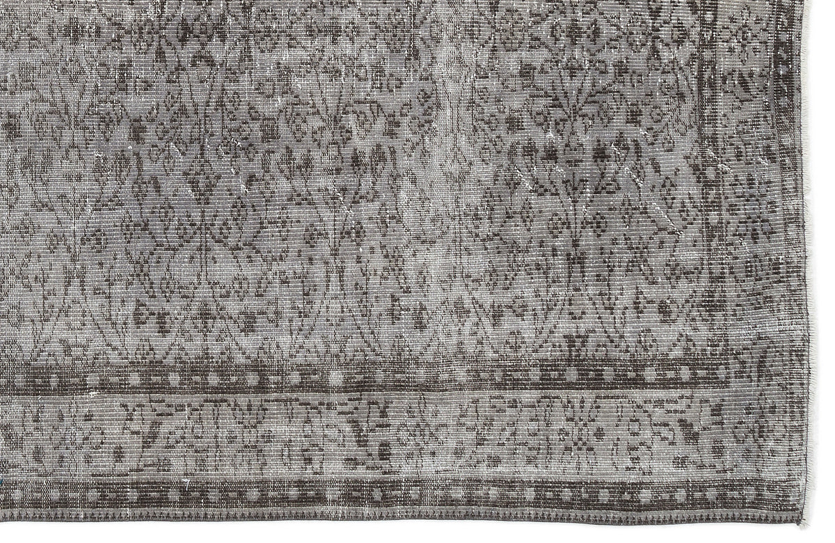 Grey and charcoal distressed rug with a traditional floral medallion pattern and a geometric border.