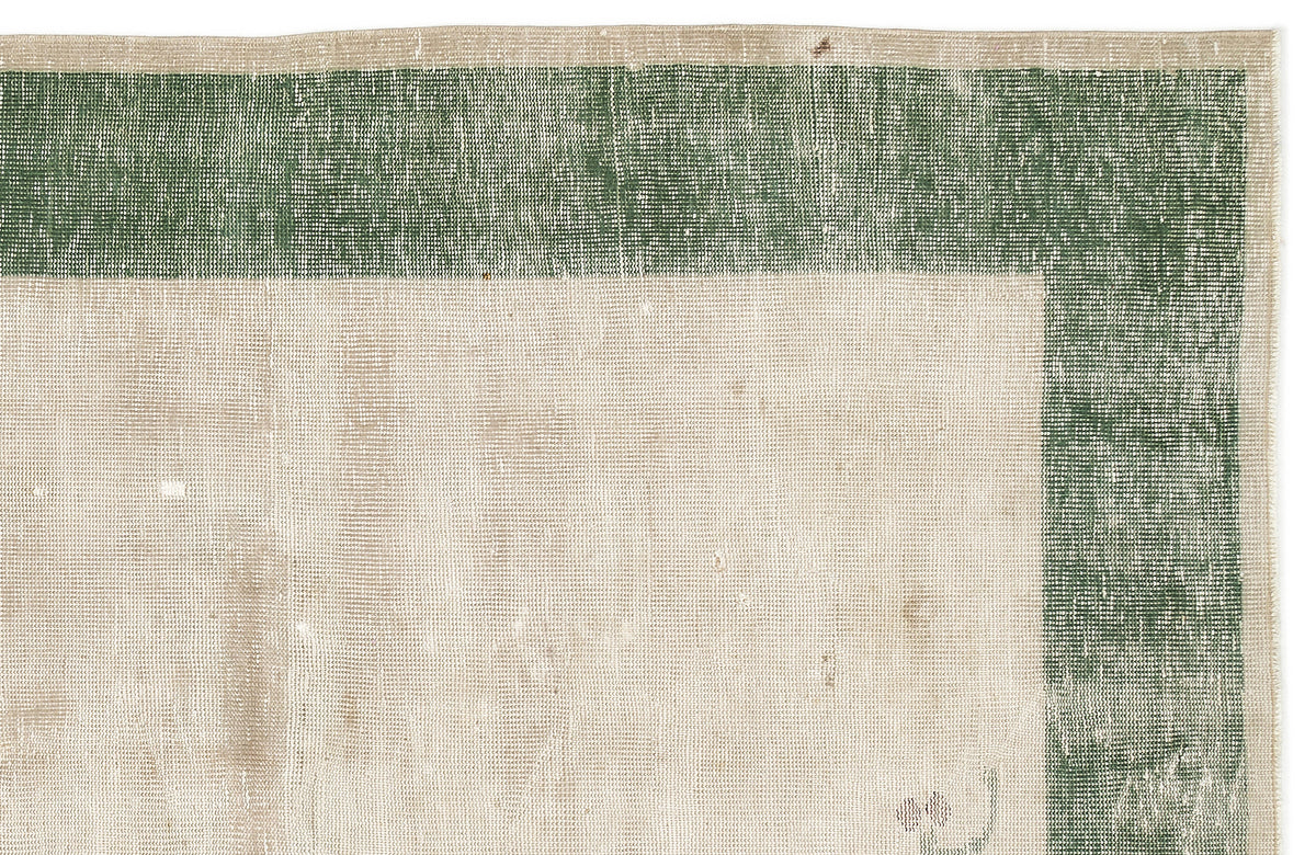Beige rug with a distressed forest green border and a flat-weave texture.