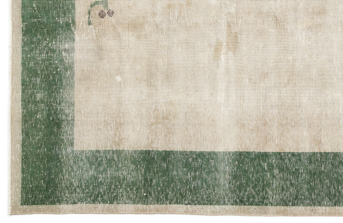 Distressed beige rug with a wide forest green border and subtle floral corner detail.