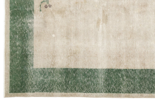 Load image 1 in gallery view. Distressed beige rug with a wide forest green border and subtle floral corner detail.
