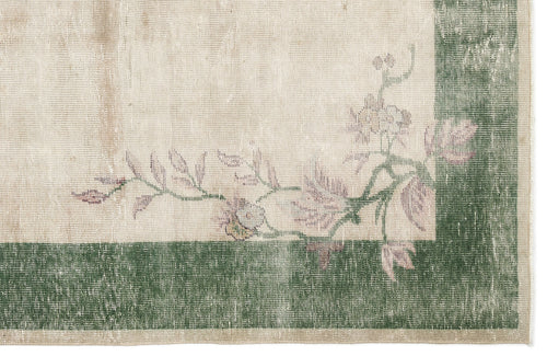 Load image 1 in gallery view. Distressed cream rug with a dark green border and faded pink floral vine pattern.