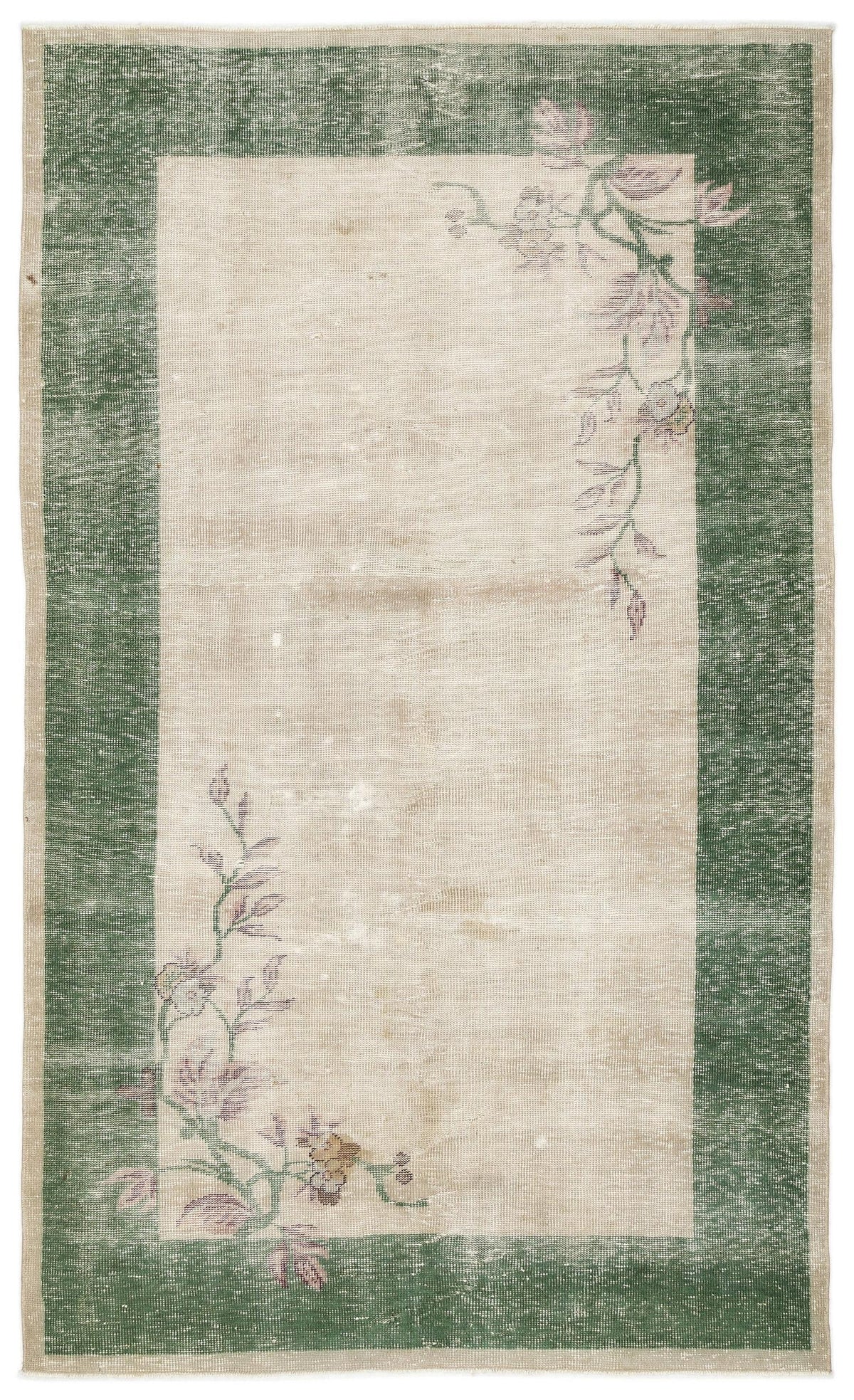 Beige rug with a dark green border and distressed floral vine motifs in the corners.