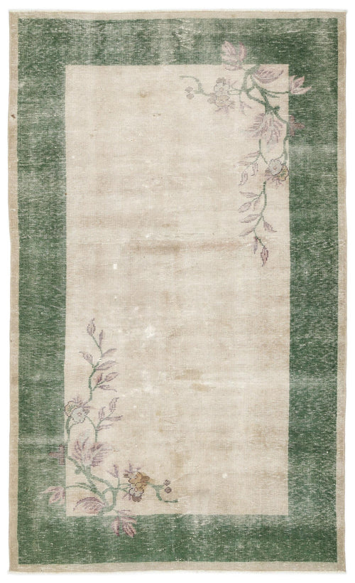 Load image 1 in gallery view. Beige rug with a dark green border and distressed floral vine motifs in the corners.