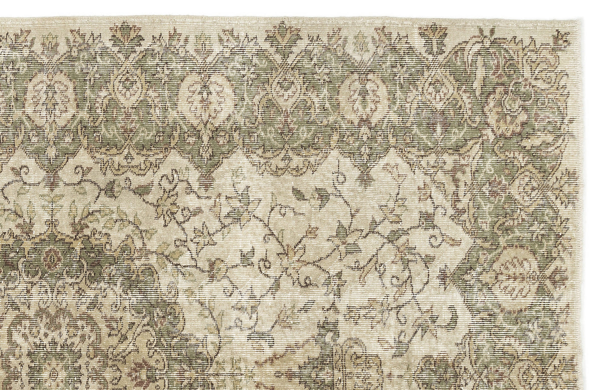 A section of the Seudian Vintage Medallion Rug (5'9 x 8'9) displays faded floral and geometric patterns in green, beige, and cream. The top border highlights repeating leaf and flower motifs, adding to its vintage charm.
