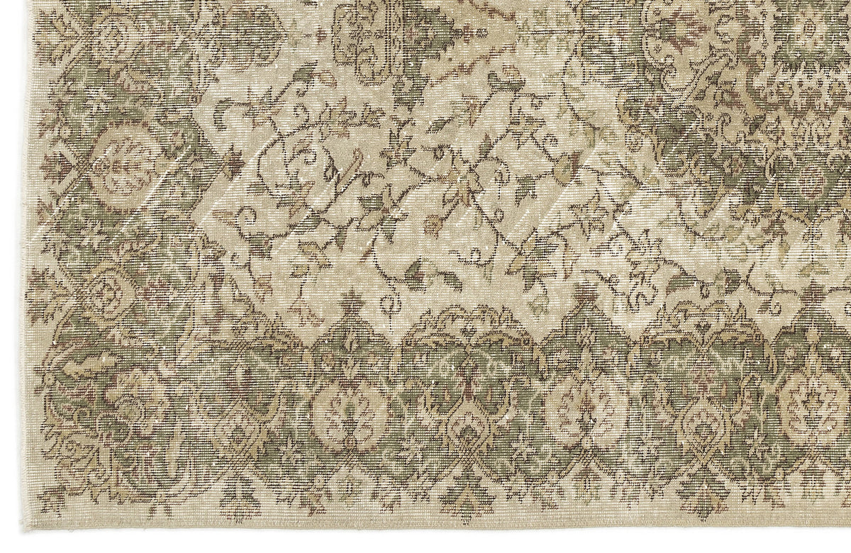 A close-up of the Seudian - Vintage Medallion Rug (5'9 x 8'9), featuring intricate floral and geometric patterns in muted beige, green, and brown. The border has repeating motifs, while swirling vine designs adorn the center.