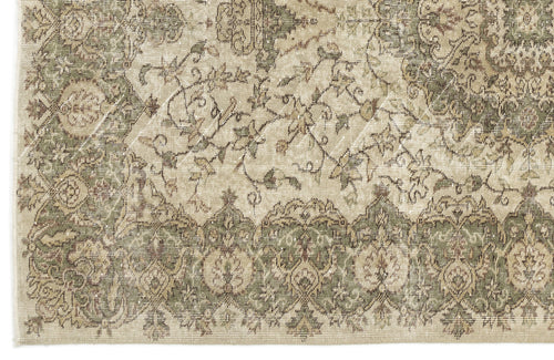 Load image 1 in gallery view. A close-up of the Seudian - Vintage Medallion Rug (5'9 x 8'9), featuring intricate floral and geometric patterns in muted beige, green, and brown. The border has repeating motifs, while swirling vine designs adorn the center.