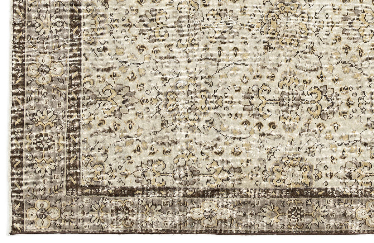Distressed beige, grey, and brown rug with a traditional floral medallion pattern and a wide decorative border.