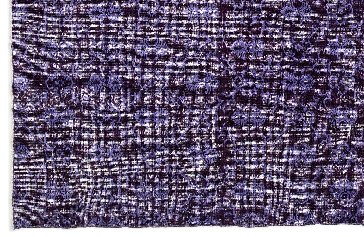 Deep purple and lavender distressed rug with a repeating floral medallion pattern.