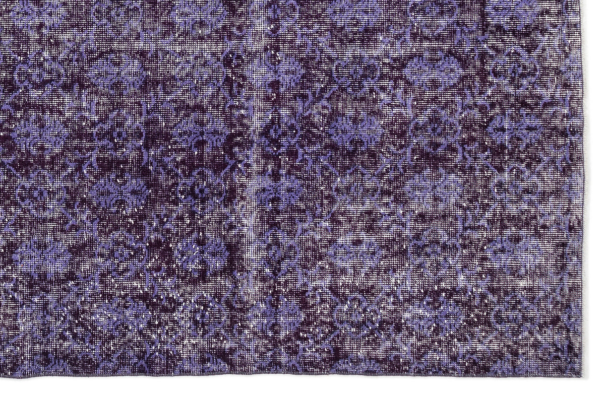 Deep purple and lavender distressed rug with a repeating floral medallion pattern.