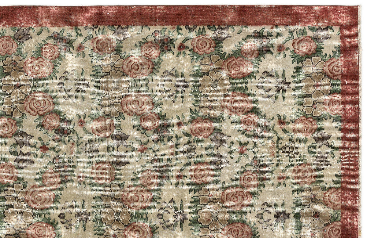 Beige rug with a repeating floral pattern in red and green, featuring a solid red border.