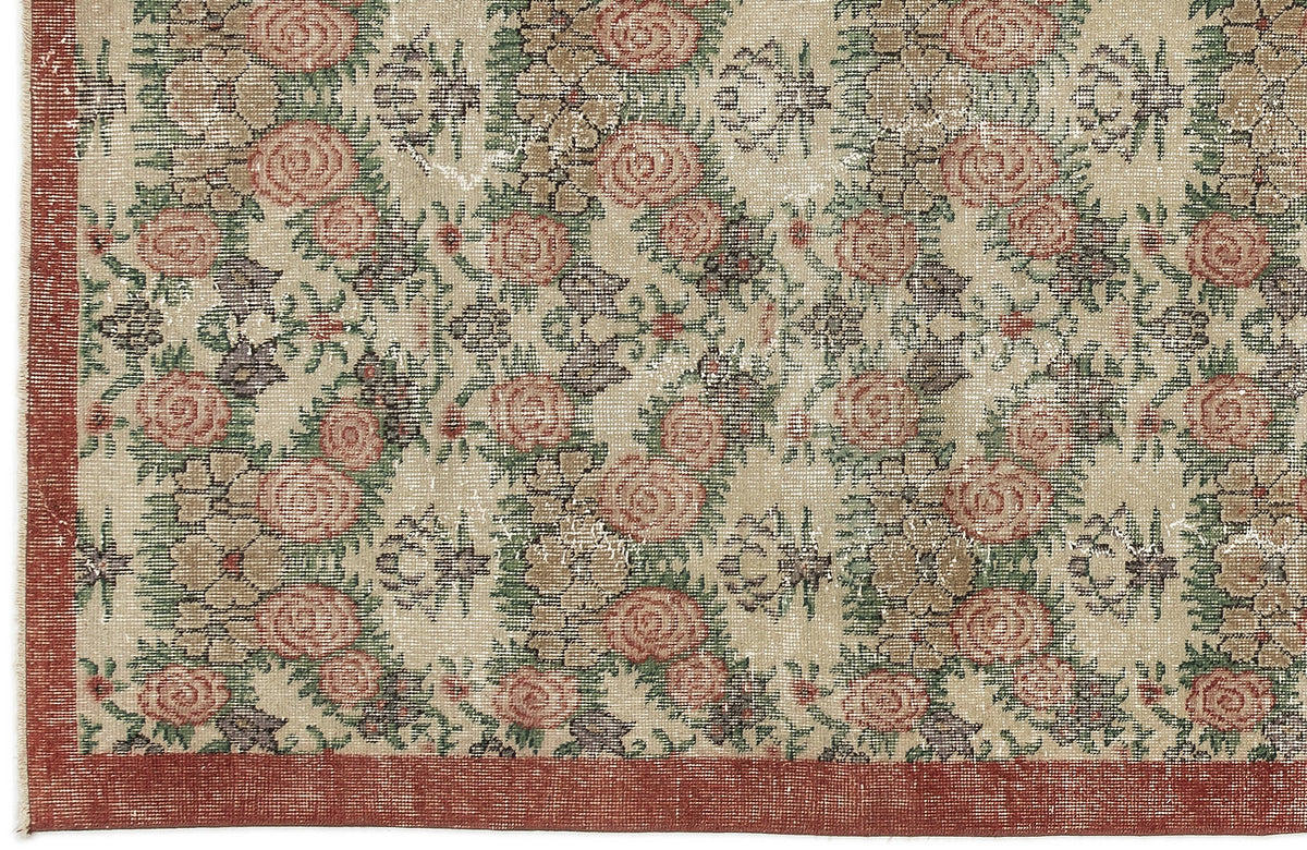 Beige rug with a distressed floral pattern in muted red and green, featuring a solid red border.