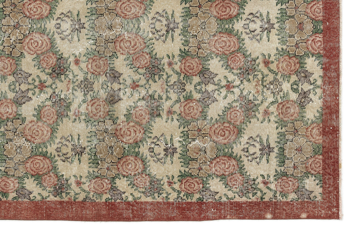 Beige rug with a distressed floral rose pattern in red and green, featuring a solid red border.
