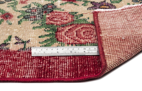 Load image 1 in gallery view. Beige rug with red floral pattern and red border, shown with a metal ruler for scale and a corner folded over.