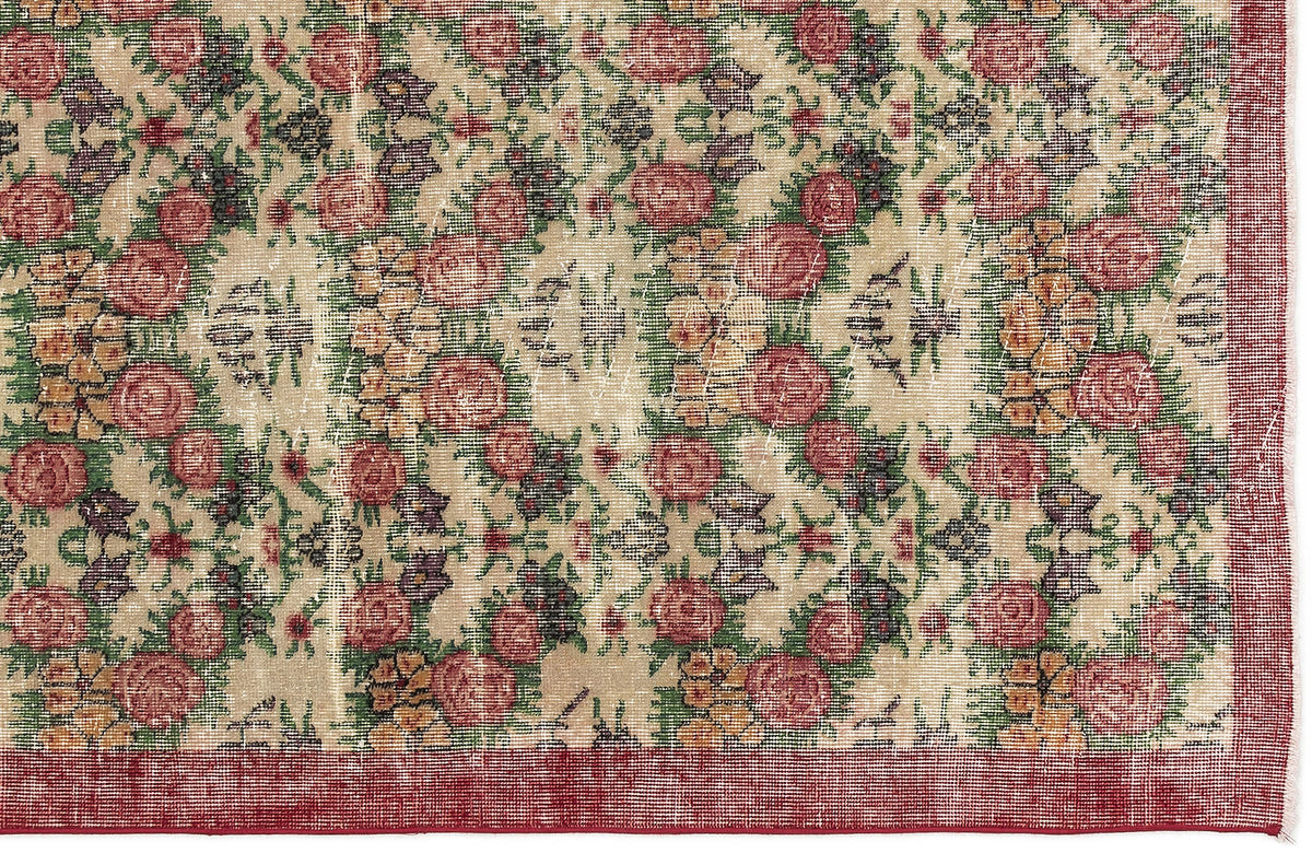 Beige rug with a distressed floral pattern in red, green, and yellow, featuring a solid red border.