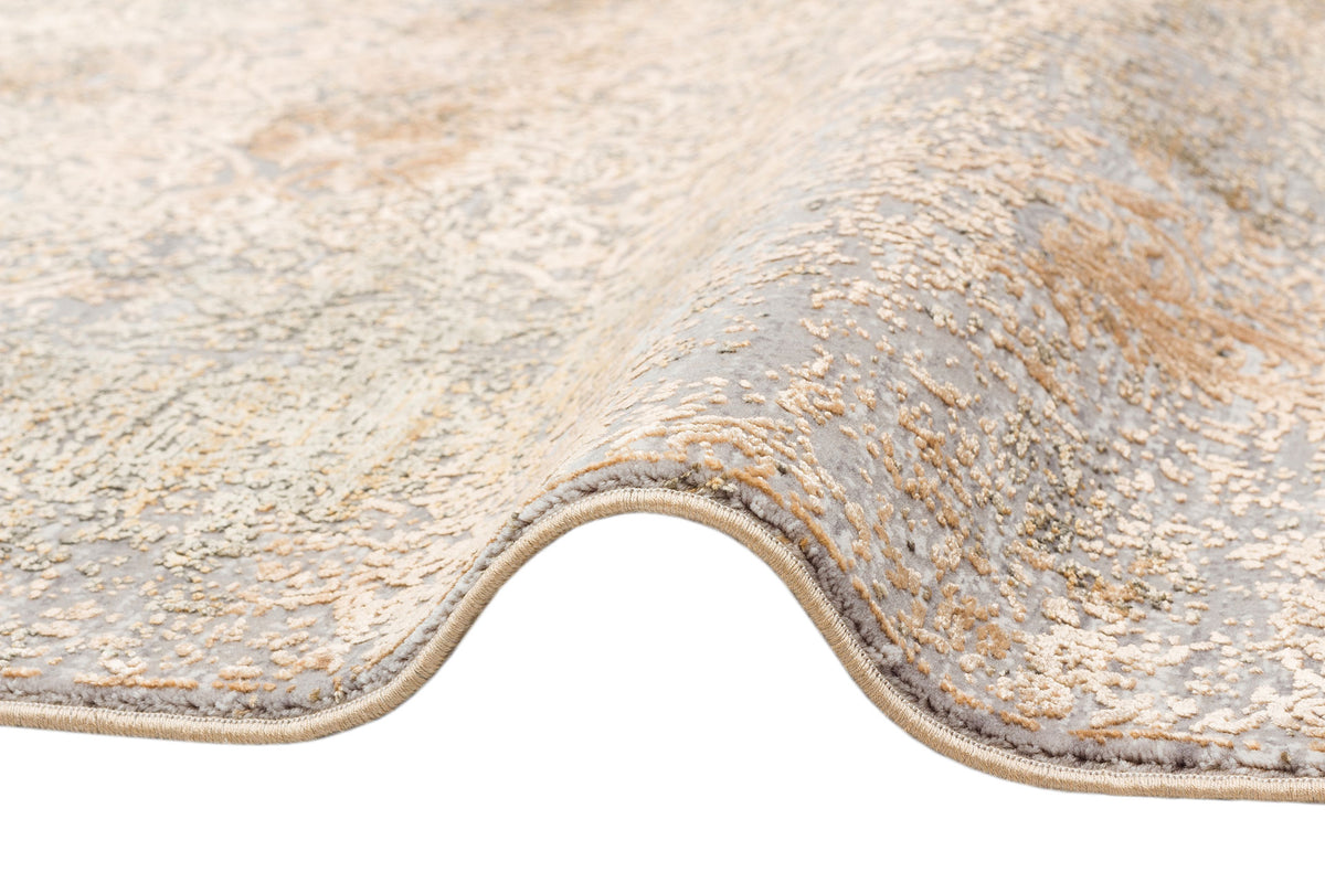 Grey and gold rug with a distressed, faded traditional pattern, shown folded on a white background.