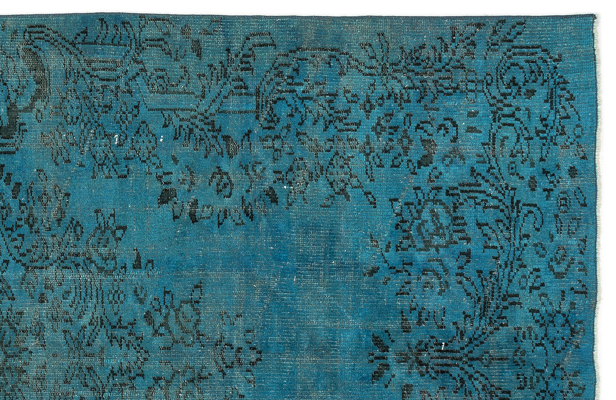 Teal rug with a distressed black floral medallion pattern on a white background.