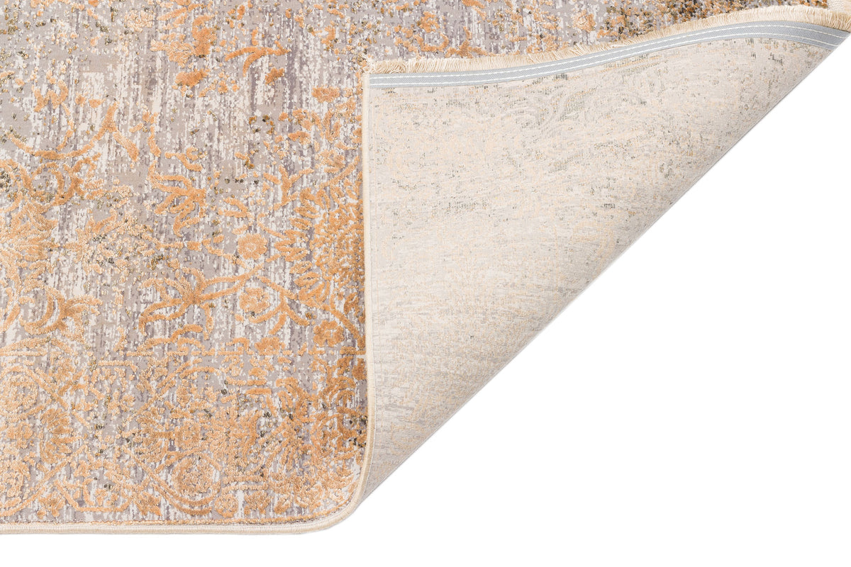 Grey and gold floral medallion rug with a distressed texture, shown with one corner folded to reveal the backing.