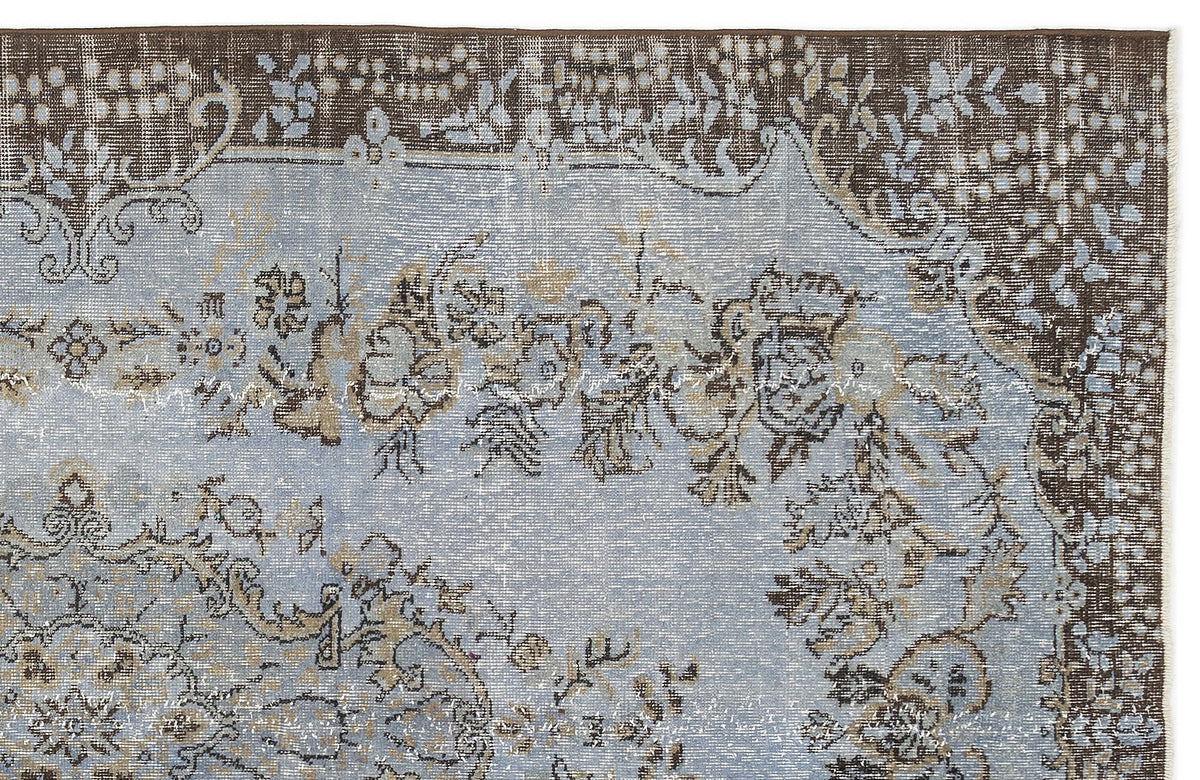 Distressed light blue rug with a dark brown border and intricate floral medallion pattern.