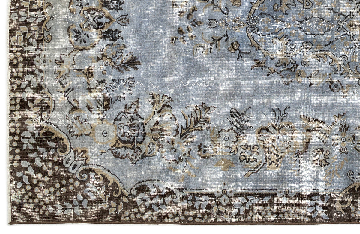 Light blue and brown distressed rug with a traditional floral medallion pattern and ornate border.