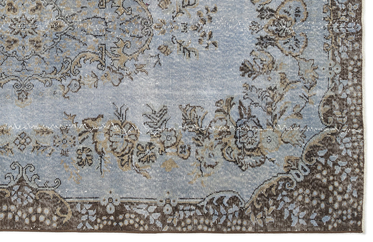 Light blue and brown distressed rug with a traditional floral medallion pattern and a dark border.